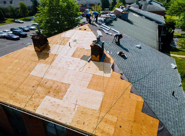 A worker checks the wooden surface of a residential roof before adding new shingles.